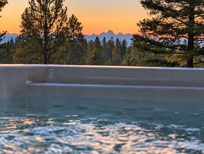 A hot tub with a view of a forest and mountains.