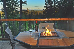 Une terrasse extérieure avec un foyer, des sièges et une bouteille de vin.