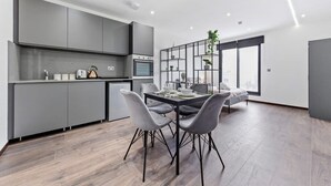 A modern kitchen with grey cabinets, a dining area with a table and chairs, and a large window providing a view.
