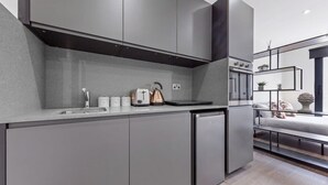 A modern kitchen with grey cabinetry, a built-in oven, and a coffee machine.