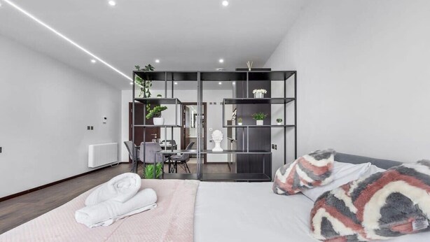 A modern hotel room with a bed, a desk, and a seating area.