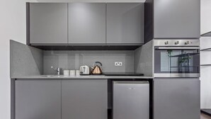 A modern kitchen with grey cabinetry, a built-in oven, and a compact refrigerator.
