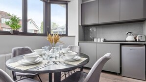 A modern kitchen with grey cabinets, a built-in oven, and a compact refrigerator.