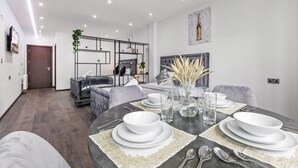 A modern dining area with a round table set for four, featuring white plates and clear glasses.