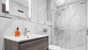 A modern bathroom with a marble vanity, a glass shower enclosure, and a toilet.