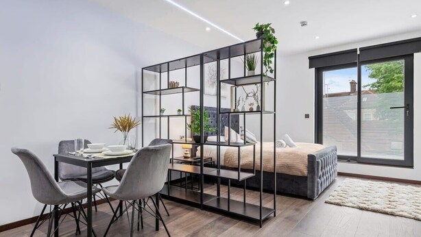Une chambre moderne avec un lit, un coin repas comprenant une table et des chaises, et une grande fenêtre offrant une belle vue.