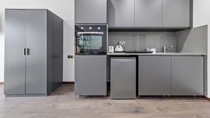 Une cuisine compacte avec des meubles de couleur grise, un four encastré et un petit réfrigérateur.