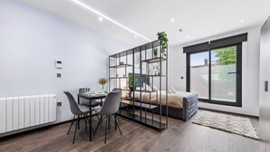Une chambre moderne avec un lit, un bureau et des chaises. Il y a une fenêtre avec des stores et un radiateur au mur.