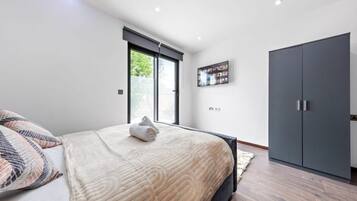 A bedroom with a bed, a wardrobe, a window with blinds, and a wall-mounted picture.