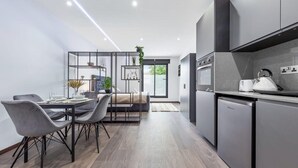 Une cuisine moderne avec des meubles de rangement aux couleurs sombres, un four encastré et un réfrigérateur compact.