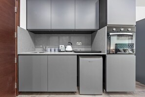 Une cuisine moderne avec des meubles gris, un four encastré et un lave-vaisselle.