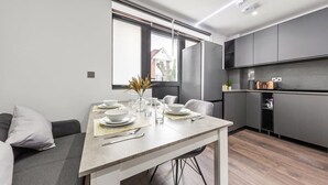 Una cucina moderna con mobili grigi, un tavolo da pranzo apparecchiato per quattro persone e un'ampia finestra che lascia entrare luce naturale.