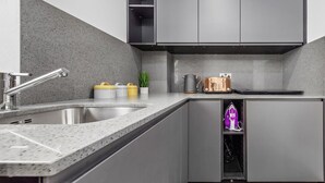 Una cucina moderna con mobili grigi, un lavello in acciaio inossidabile e un centro stiratura integrato.