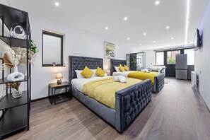 Un dormitorio moderno con una cama grande, mesitas de noche, un espejo y un televisor.