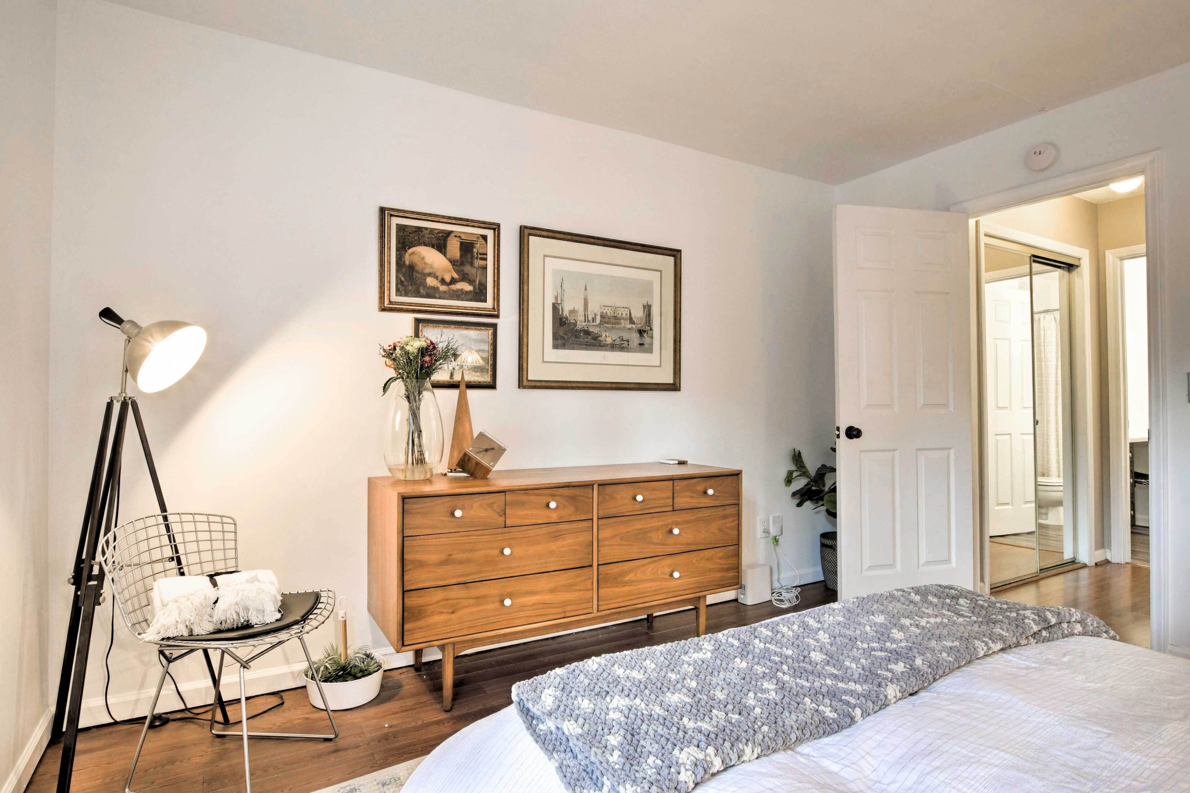 A bedroom with a bed, a dresser, a chair, and a lamp.