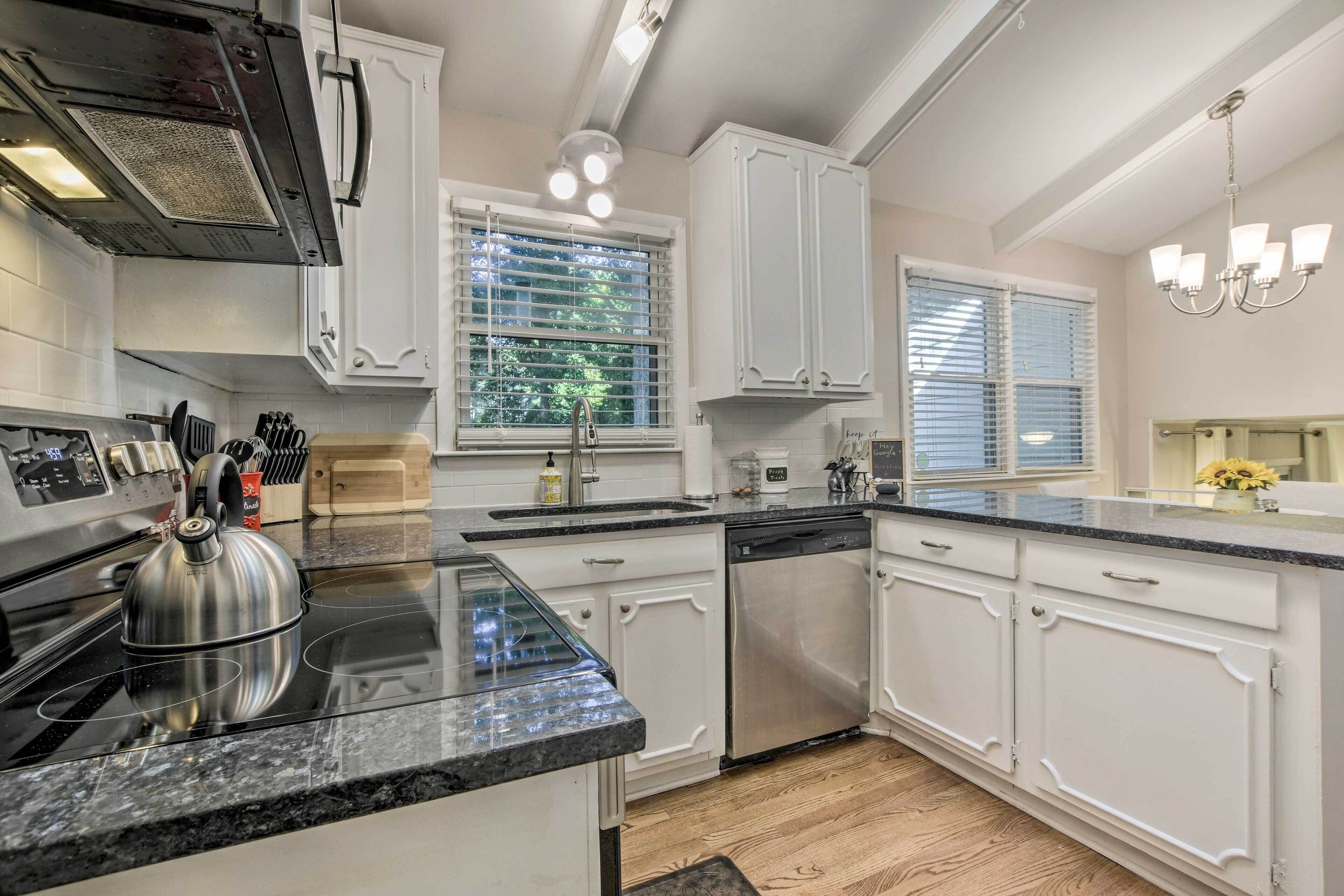 A modern kitchen with white cabinetry, a stainless steel kettle, and a dishwasher.