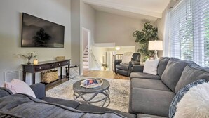 A living room with a gray sofa, a round coffee table, and a dark console table with a lamp. - Renovated Raleigh Retreat w/ Patio in North Hills! (Raleigh)
