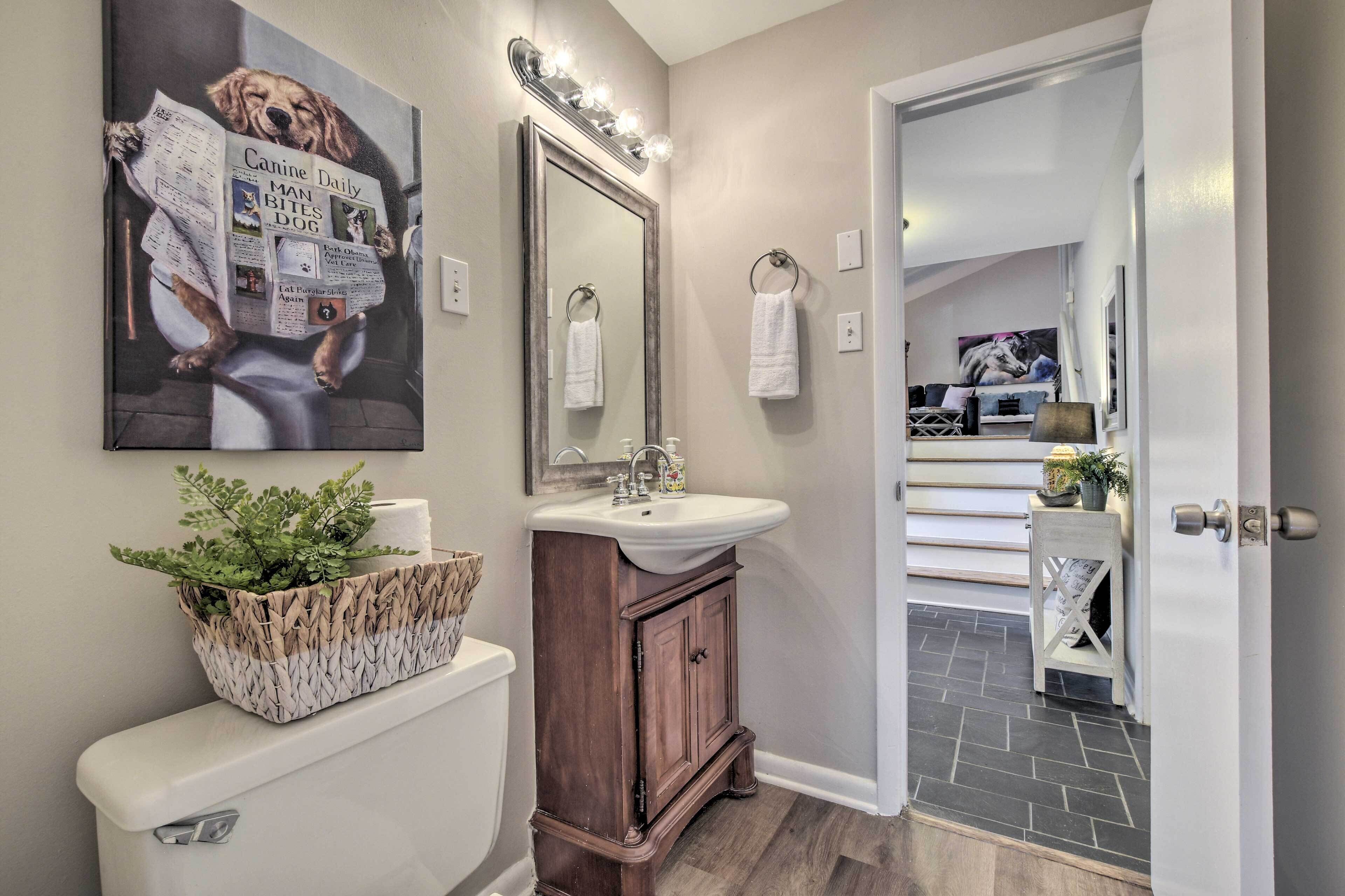 A bathroom with a toilet, sink, vanity, and a large mirror.