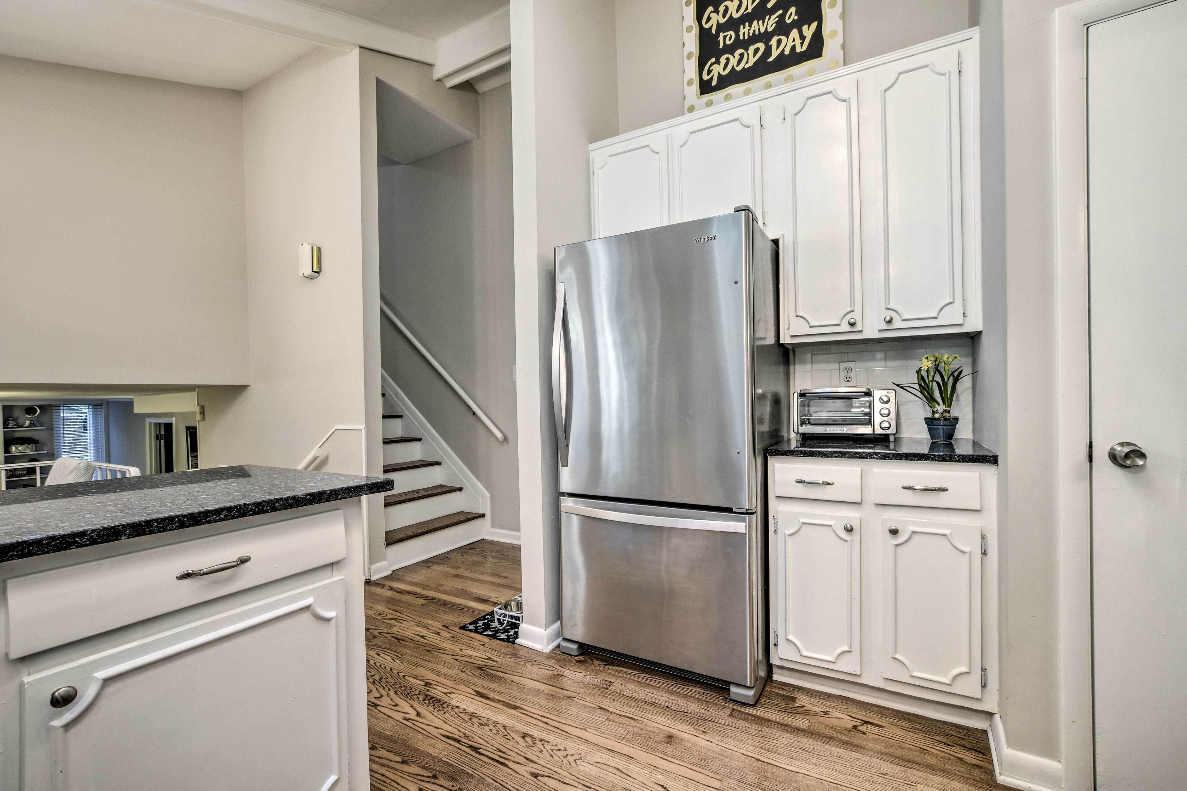 A kitchen with white cabinets, a stainless steel refrigerator, a microwave, and a toaster.