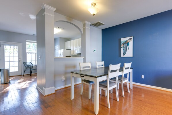 A dining area with a table and chairs, a kitchen in the background, and a blue accent wall. - Townhome w/ Community Pool: 11 Mi to Dtwn Raleigh! (Raleigh)