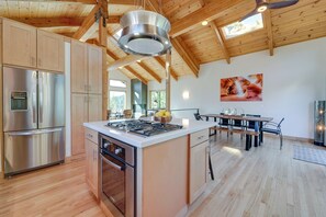 A spacious kitchen with wooden beams, stainless steel appliances, and a large island.