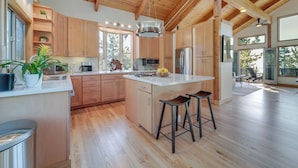 Une cuisine moderne avec des meubles en bois, un îlot central et des tabourets de bar.