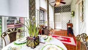 A dining area with a table set for four, a ceiling fan, and a view of the outside. - Jennys Southland Homestead, LLC (Oakland)