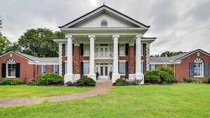 A large, symmetrical building with a central entrance flanked by two wings, each with a brick facade and white trim. - Jennys Southland Homestead, LLC (Oakland)