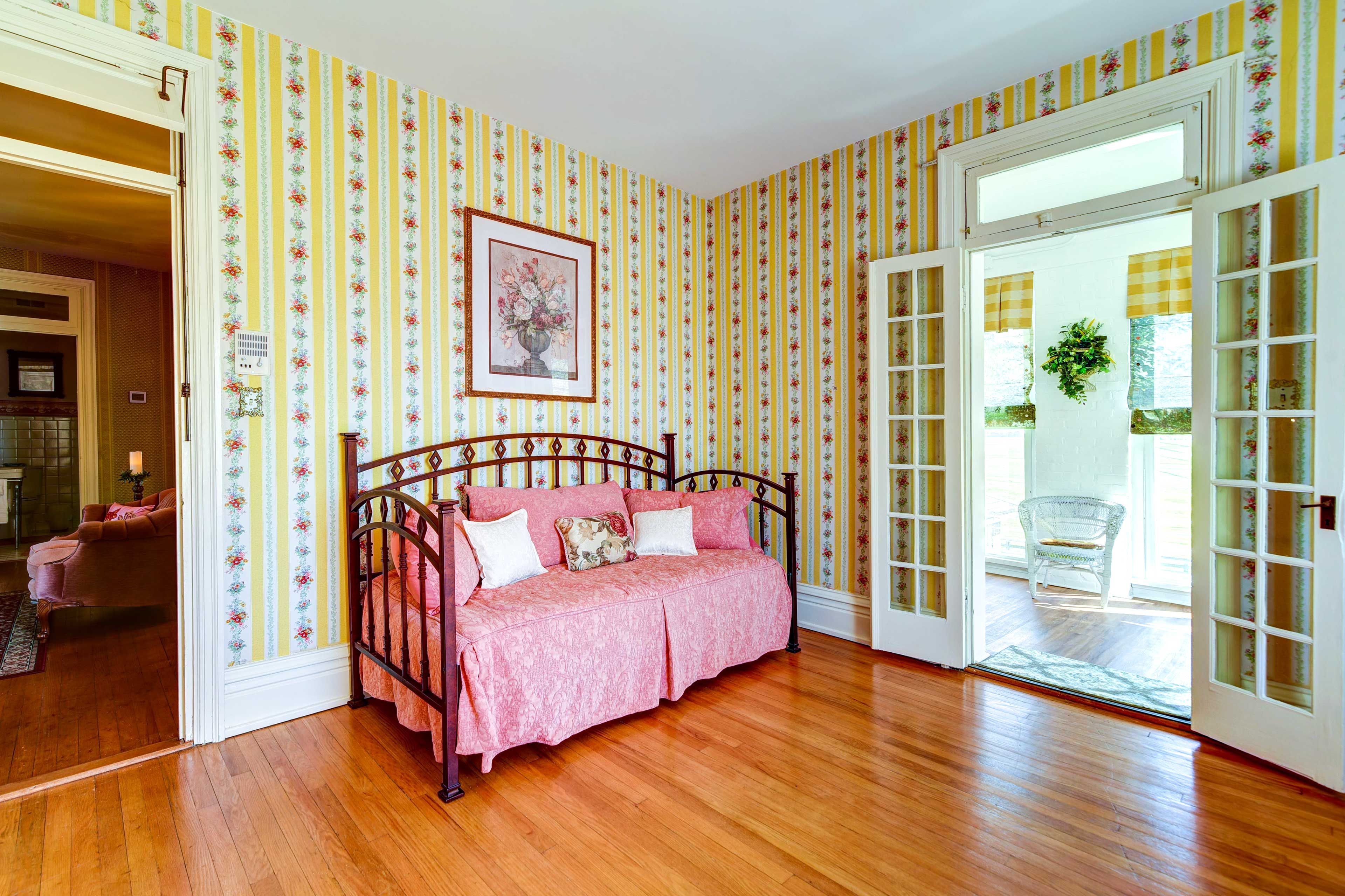A room with a bed, a door leading outside, and a framed picture on the wall.