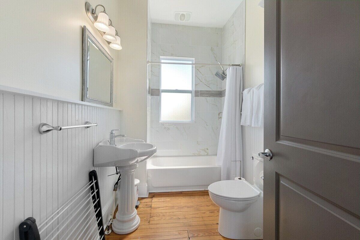 Une salle de bain avec une baignoire, deux lavabos, des toilettes et un rideau de douche.