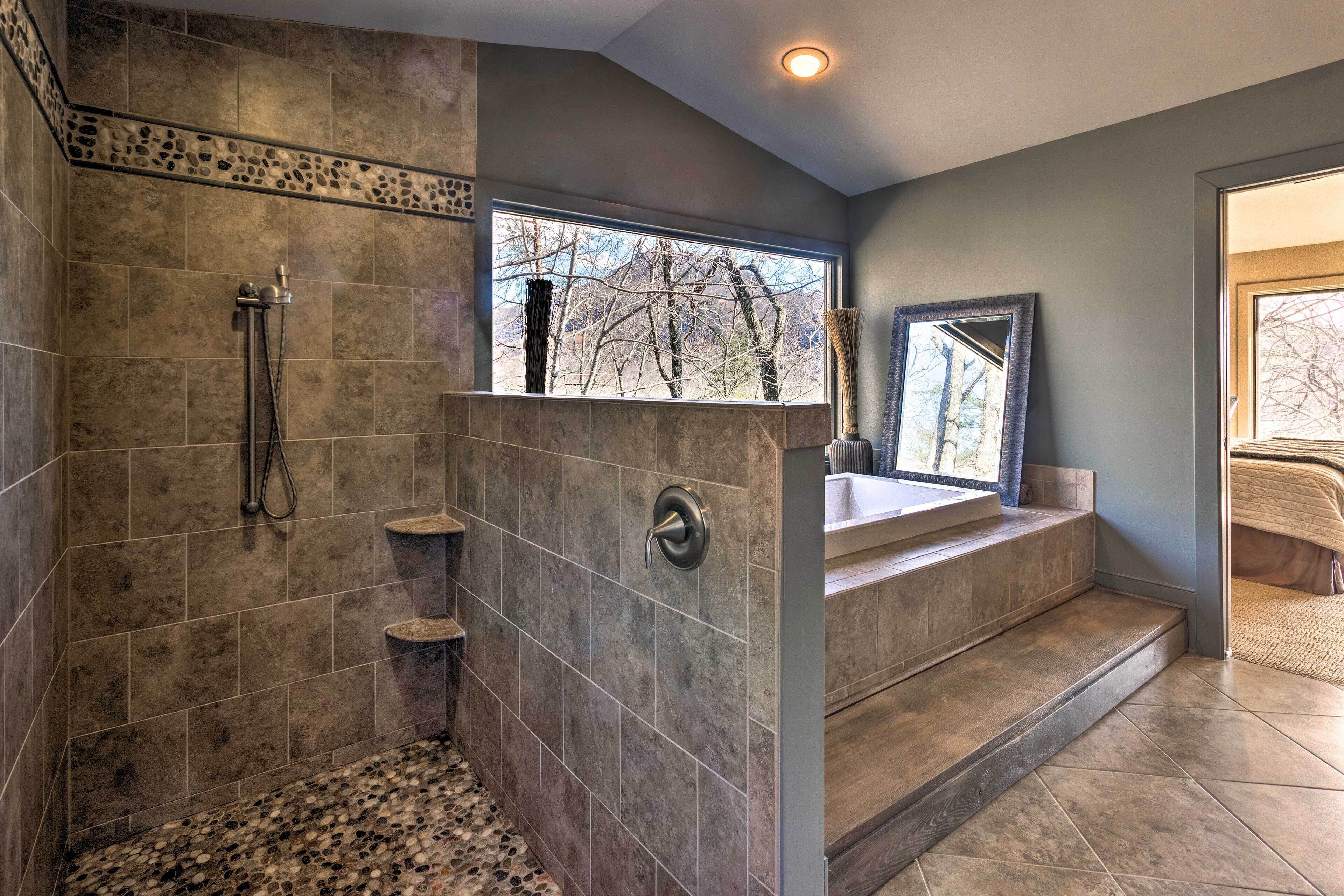 A bathroom with a shower, a window with a view, and a bathtub.
