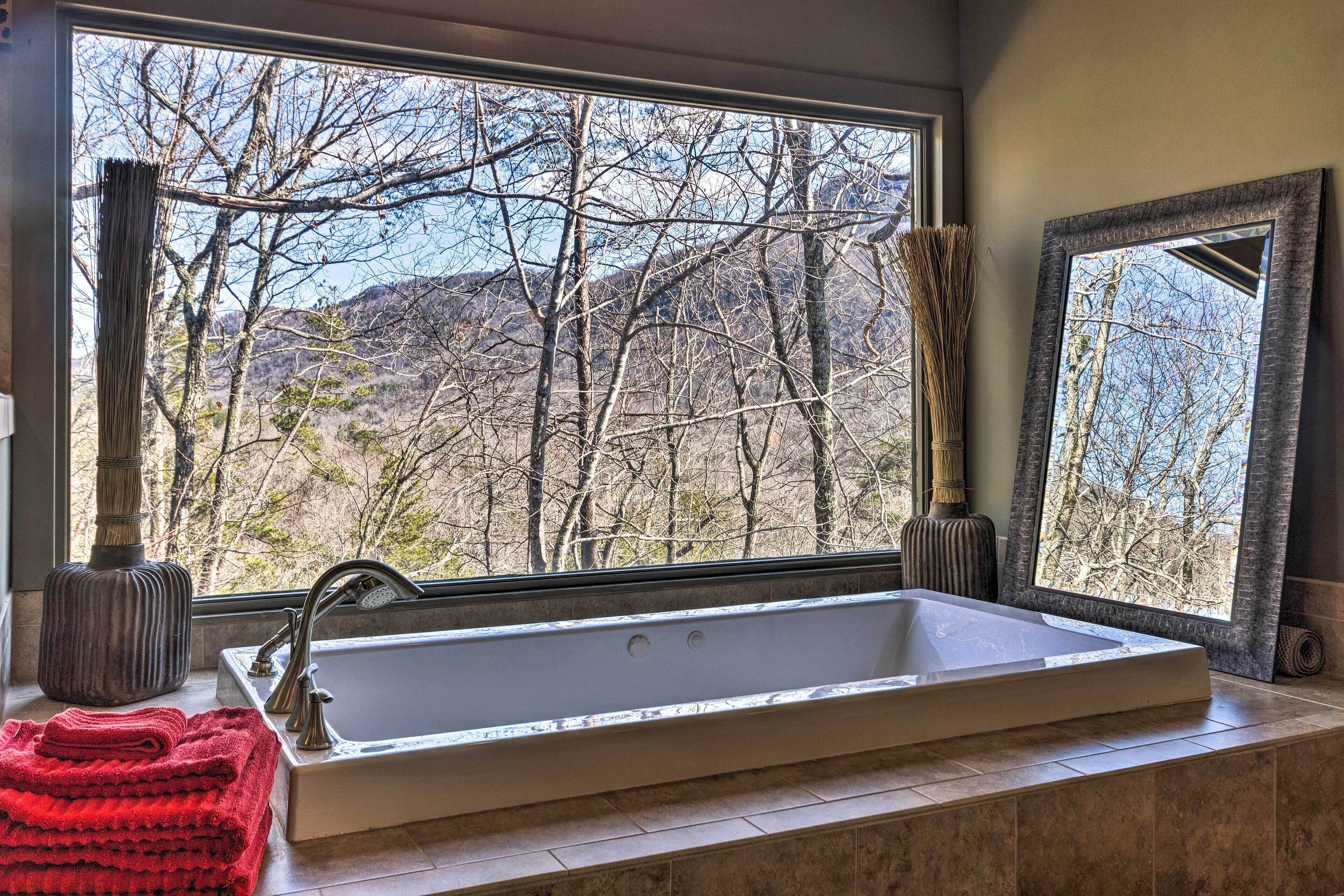 Ein Badezimmer mit großem Fenster, einer Badewanne und einem Spiegel.