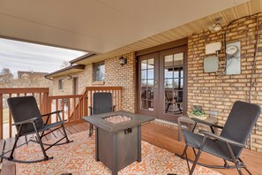 A covered patio with a fire pit, two rocking chairs, and a table with a basket of plants. - Parowan Escape With 2 Game Rooms, Deck & Yard! (Parowan)