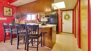 Una cucina con mobili in legno, un frigorifero nero e una zona pranzo con sedie e tavolo in legno.