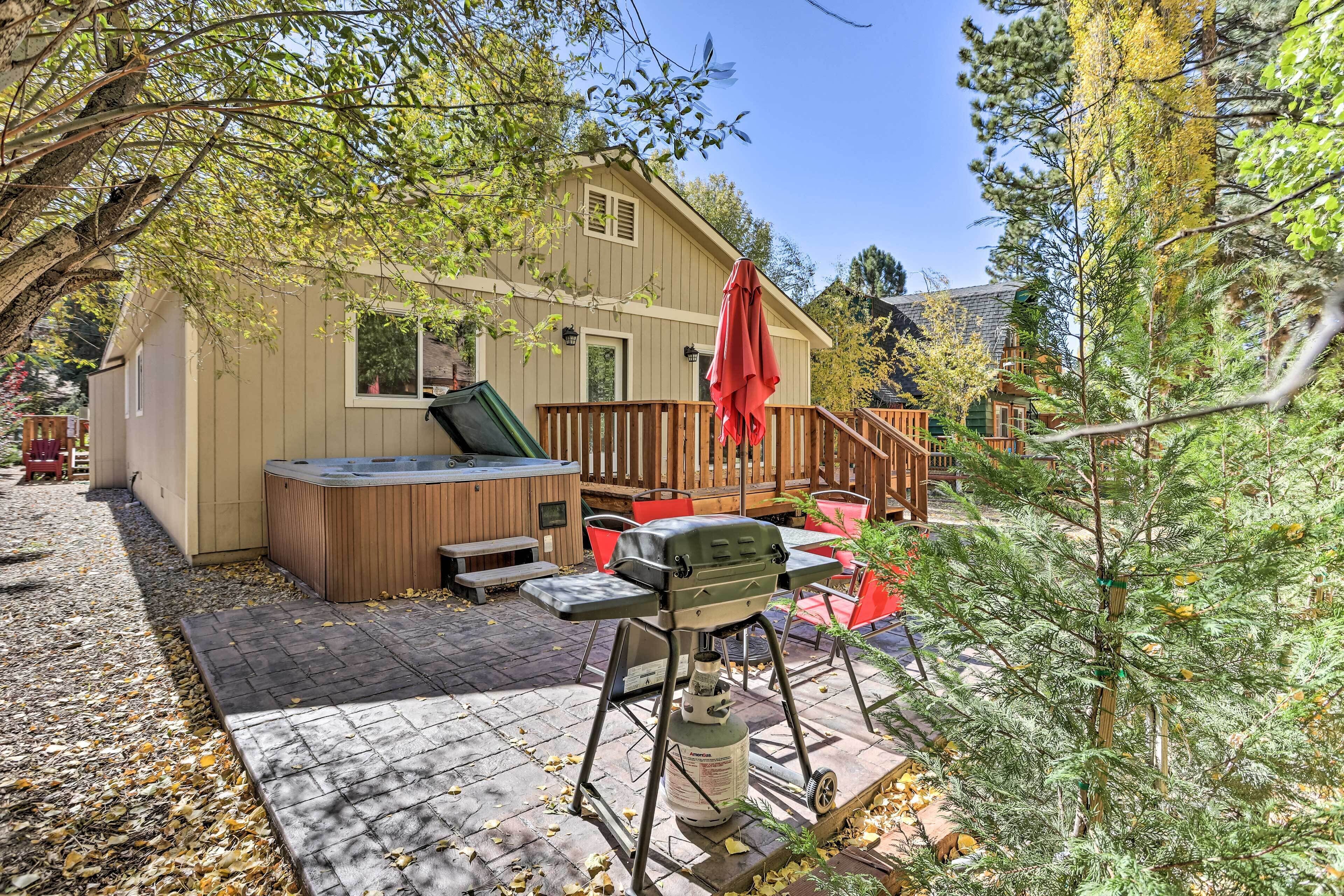 A backyard with a hot tub, barbecue grill, and outdoor seating area.