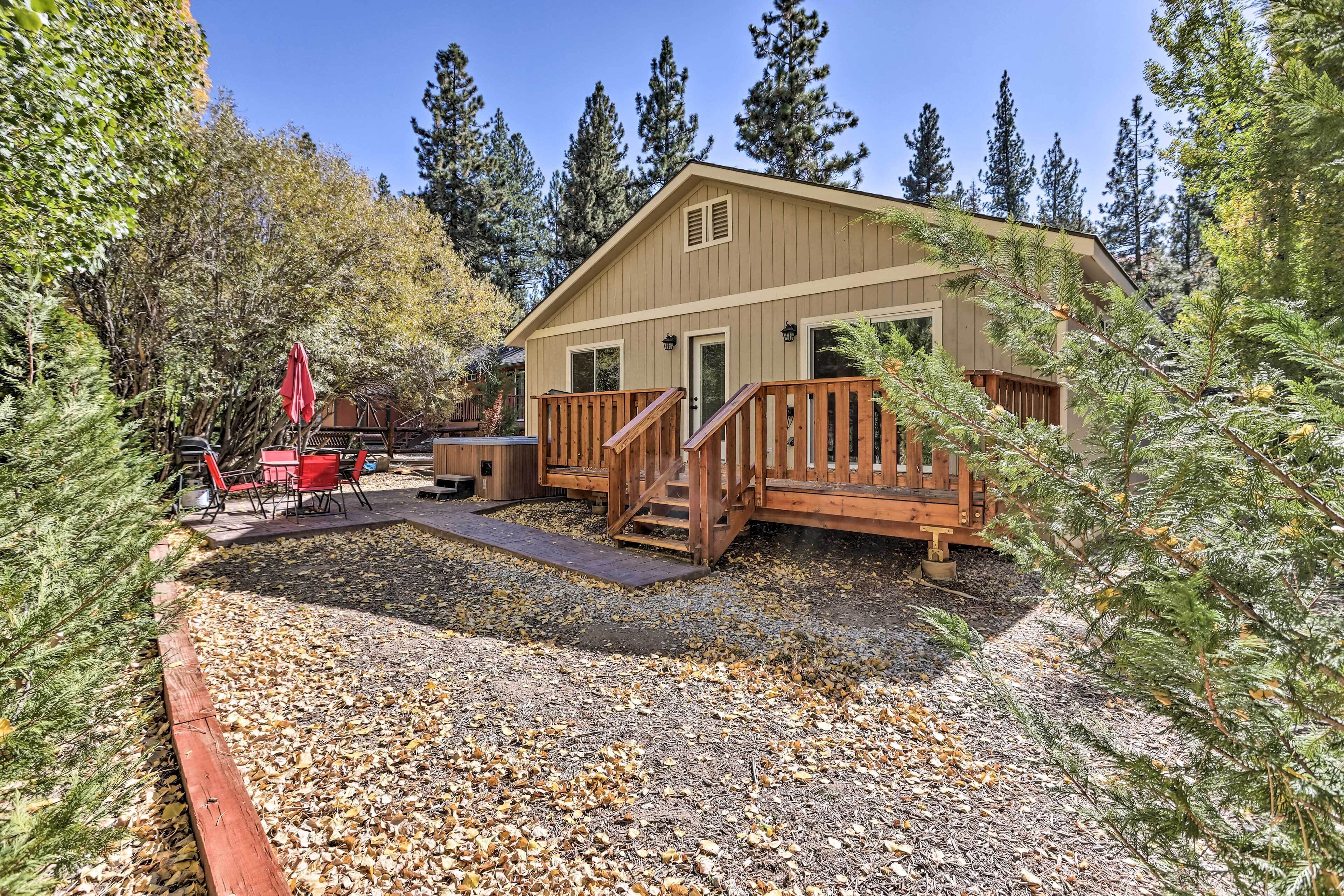 A cabin with a wooden deck, a covered patio, and a small outdoor seating area.