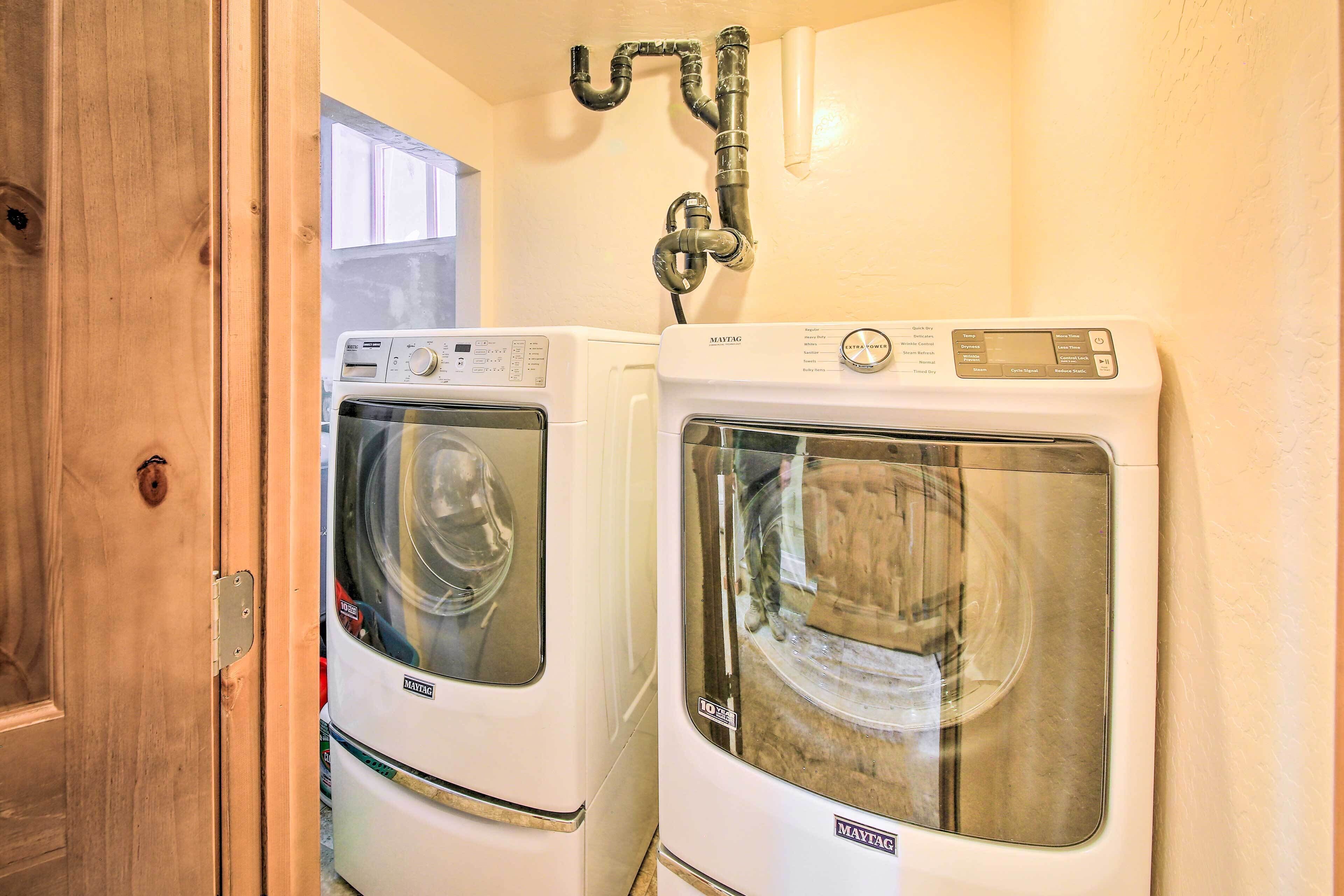 Two front-loading Maytag washers in a laundry room with a wooden door and a visible window.
