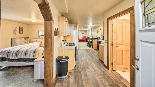A compact hotel room with a bed, a small kitchenette, a trash bin, and a wooden door. - Priest Lake Apartment Near Hiking Trails! (Priest River)