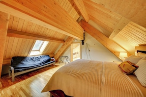 A cozy attic bedroom with a bed, a bench, and a skylight. - Lake Pend Oreille Oasis: Home w/ Hot Tub & Games (Sagle)