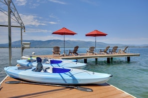 A dock with kayaks, lounge chairs, and red umbrellas. - Lake Pend Oreille Waterfront With Amazing Views (Sagle)