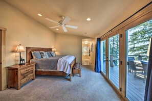 A bedroom with a bed, bedside tables, a ceiling fan, and a view of an outdoor deck. - Lake Pend Oreille Waterfront With Amazing Views (Sagle)