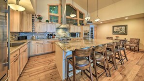 Una cocina amplia con armarios de madera, una isla grande con taburetes de bar y un comedor con sillas.