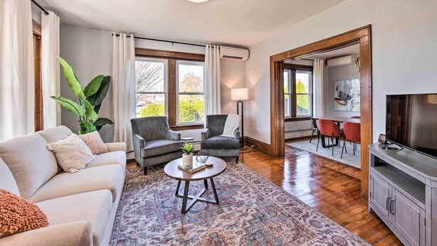 Un salon comprenant un canapé, deux fauteuils, une table basse, un téléviseur et un coin repas avec des chaises et une table.