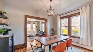 Une cuisine moderne avec une table à manger en bois, des chaises et un luminaire suspendu.