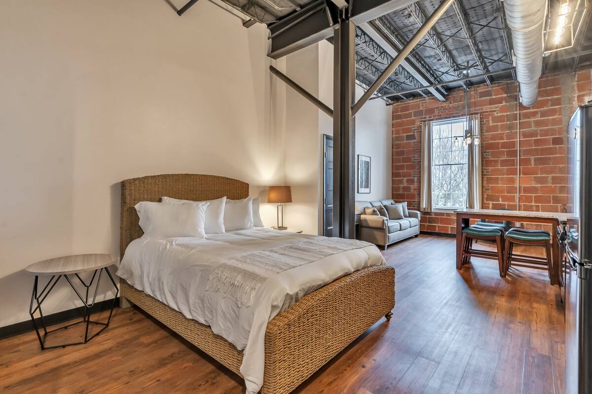 A bedroom with a wicker bed, a small table, and a bench.