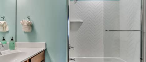 A modern bathroom with a glass-enclosed shower, a white sink, and a mirror.