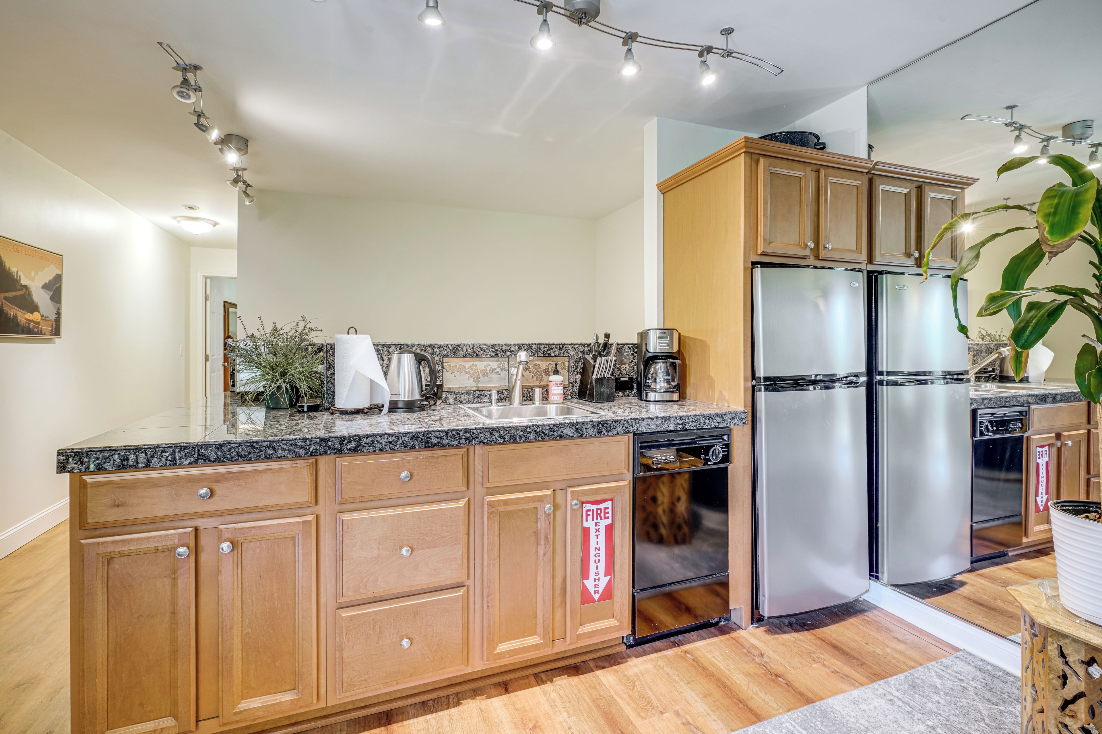 A modern kitchen with wooden cabinets, a stainless steel refrigerator, and a built-in dishwasher.