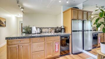 A modern kitchen with wooden cabinets, a stainless steel refrigerator, and a built-in dishwasher.