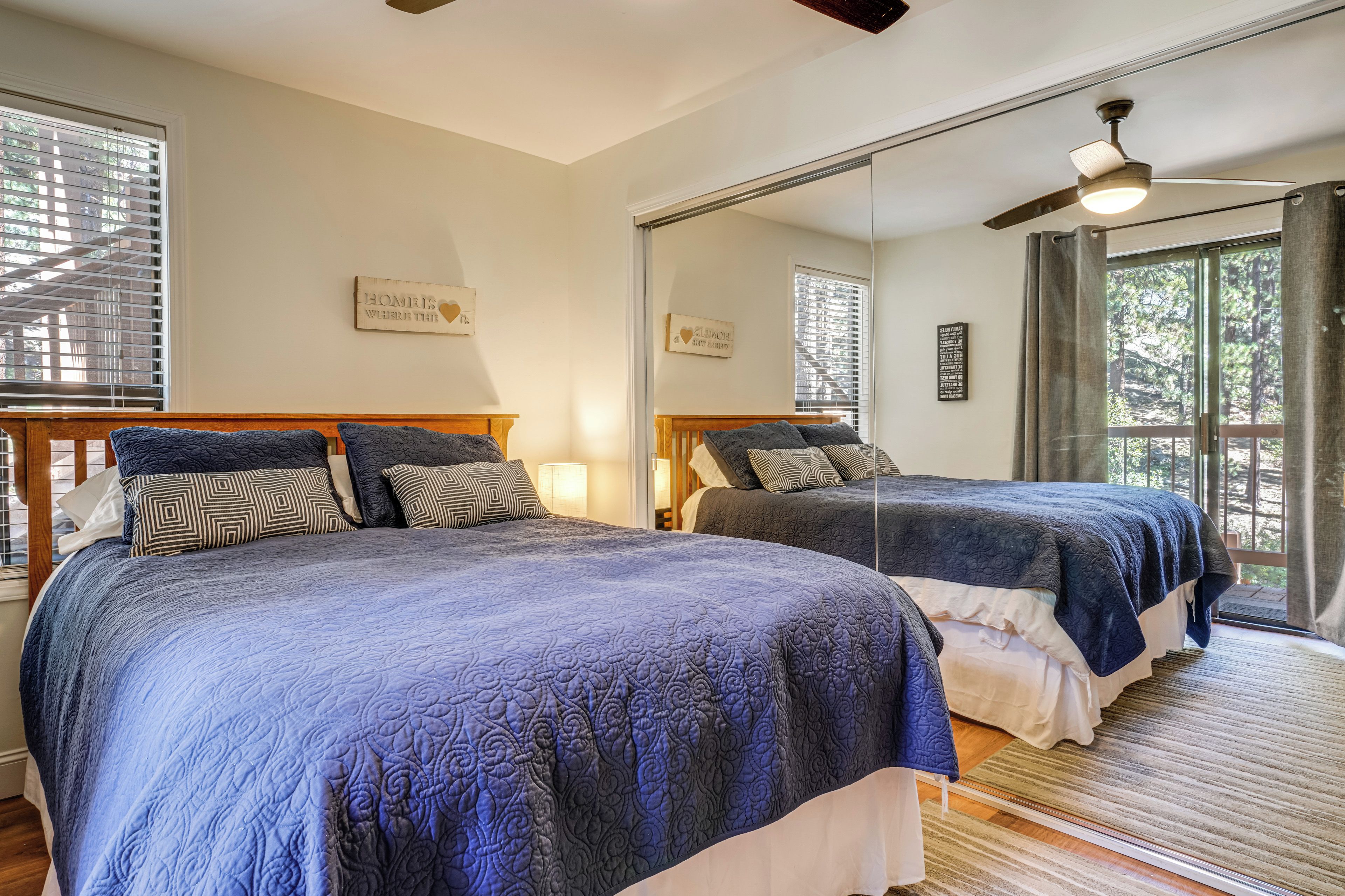 A bedroom with two beds, a large mirror, and a ceiling fan.