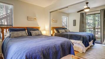 A bedroom with two beds, a large mirror, and a ceiling fan.
